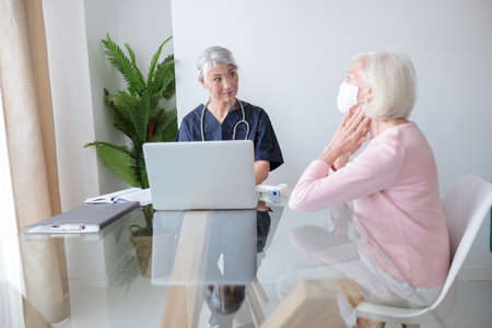 Elderly woman in mask sitting at doctor officeの写真素材