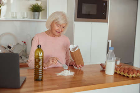 Aged housewife making dough for biscuits in kitchenの写真素材