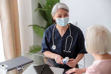 Adult pediatrician talking with old woman at homeの写真素材