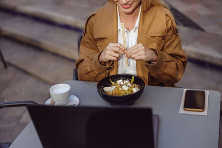 Portrait of woman sitting in cafe, holding chopsticksの写真素材