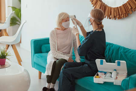 Female doctor checking elderly patient at homeの写真素材