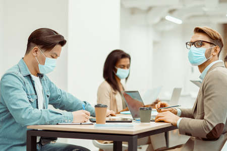 Two men and woman working at the table in the officeの写真素材
