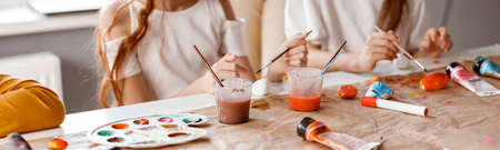 Smiling schoolgirls making art painting using water colors
