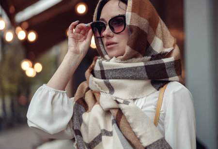Portrait of beautiful young lady in sunglasses with scarf covering head. Stylish woman.