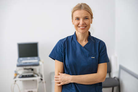 Smiling doctor, ultrasound specialist looking at camera on her workplace in clinic