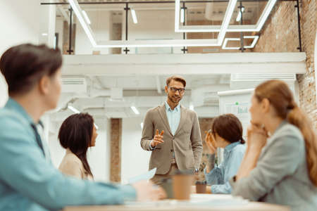 Man standing in office and explaining new ideas to colleaguesの写真素材
