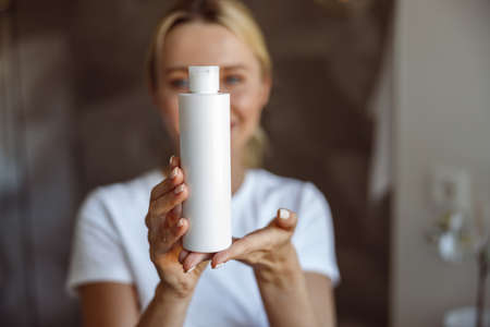 Close up of face lotion or moisturizer in hands of attractive young blonde woman. Beauty care.の写真素材