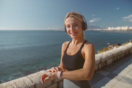 Smiling young sportswoman doing warm-up exercise standing near seaの写真素材