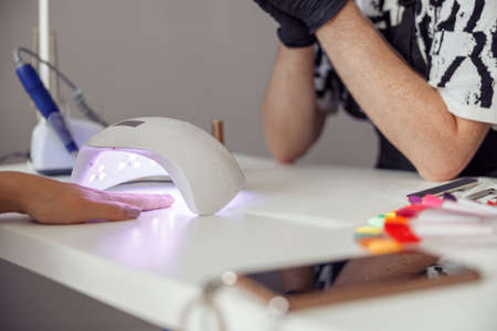 Manicure specialist doing nail care for client in studioの写真素材