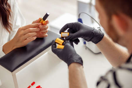 Nail technician with nail polishes in manicure salon