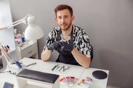 Professional nail master sitting at working place in salonの写真素材