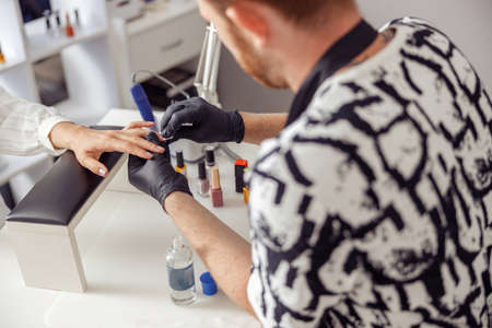 Manicure master doing nail care for client in work studioの写真素材