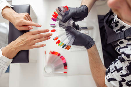 Manicure master helping to choose polish color in studioの写真素材
