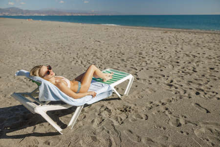 Attractive woman relaxing on the beach and looking at the seaの写真素材