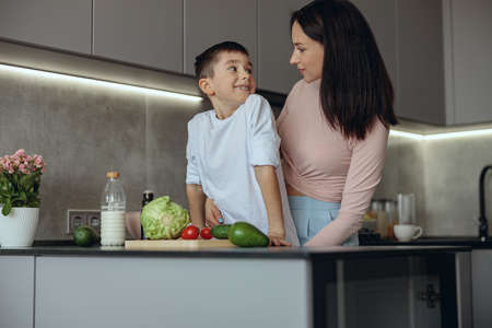 Portrait shot pf beautiful mother and little con looking at each other in kitchen.