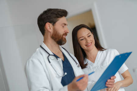 Two doctor colleagues discussing patient diagnosis stand in clinic hallの写真素材