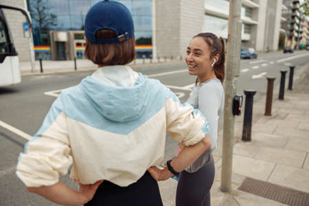 Two sportive young female friends walking city after morning running