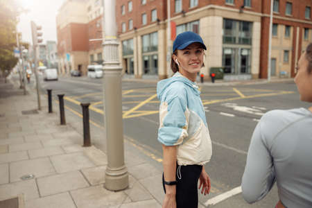 Two sportive young female friends walking city after morning running. Blurred background