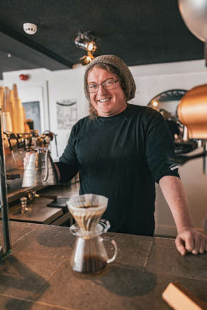 Hand drip coffee, Barista pouring water on coffee ground with filter and looking camera