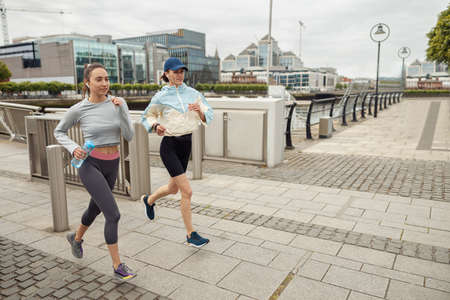 Two athletic women in sportswear are running around the city. Reaching the goalの写真素材