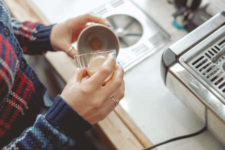 Woman pouring coffee into mug while working in cafeの写真素材
