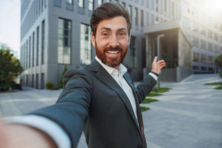 Happy businessman in suit make a selfie on background of his office buildingの写真素材