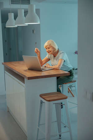 Aged woman having webcam call on laptop indoorsの写真素材