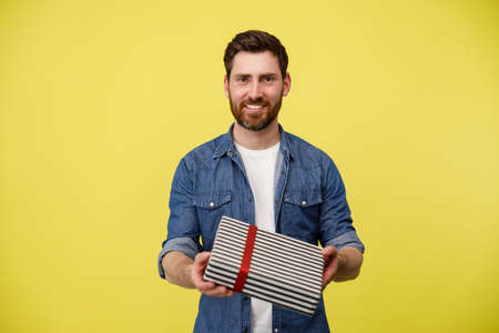 Portrait of happy man giving wrapped gift box and smiling at camera. This present for youの写真素材