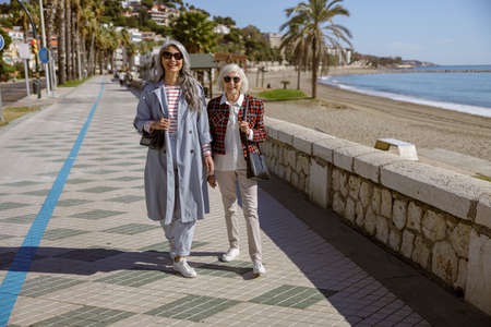 Two ladies on walk through promenade by seaの写真素材