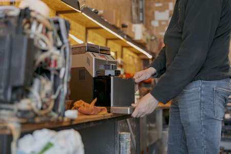Professional worker inspecting detail of coffee machine in workshopの写真素材