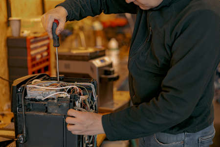 Male electrician hands repairing coffee machine in workshopの写真素材