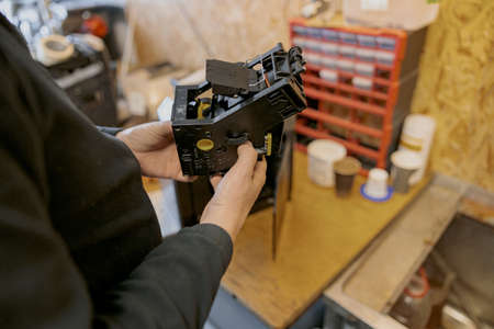 Professional worker inspecting detail of coffee machine in workshop
