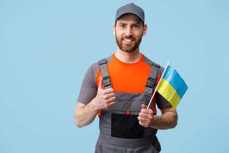 Smiling Worker employee man in uniform holding ukrainian national flag in handの写真素材