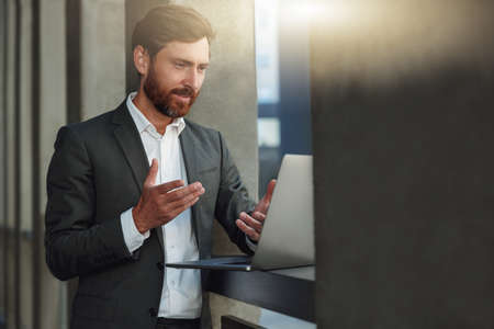 Smiling businessman make videocall to client standing near office building