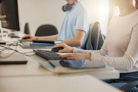 Close up of university student using computer studying in computer roomの写真素材