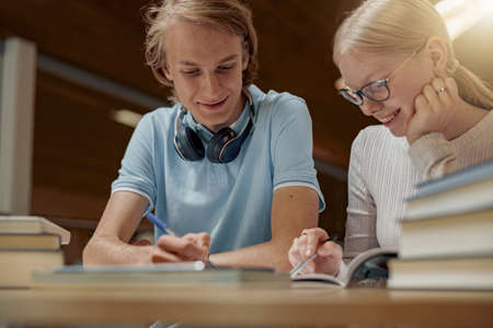 Students sit in the library and take notes while preparing for the examの写真素材