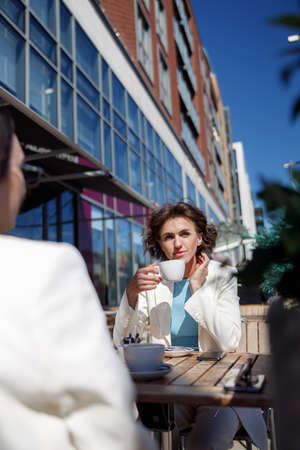 Two attractive female friends drinking coffee sitting in cafeの写真素材