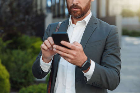 Close up of unrecognisable businessman with phone standing near office building