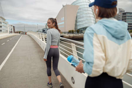Two sportive young female friends walking city after morning running