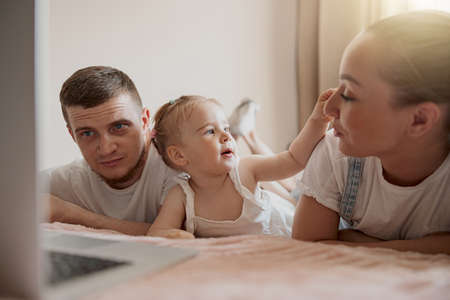 Close up of happy family having fun together watching cartoons online on laptop lie on sofa at homeの写真素材