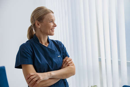 Portrait of female doctor in uniform standing in medicine clinic hall and looking awayの写真素材