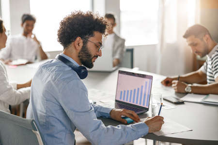 Group of young diverse coworkers analyzing sales report while working together in the office