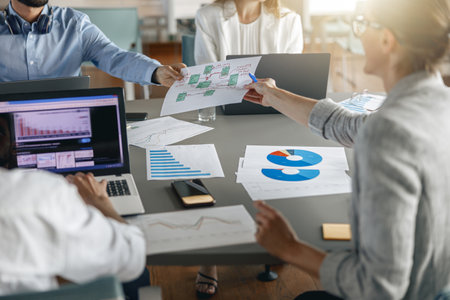 Group of busy coworkers working together analyzing the charts in modern officeの写真素材