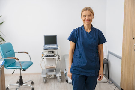 Smiling doctor, ultrasound specialist looking at camera on her workplace in clinicの写真素材