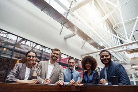 Group of happy, motivated business people standing together at office with their leader