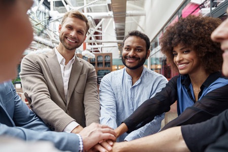 Happy group of multi ethnic coworkers stacked hands together as concept of corporate unity
