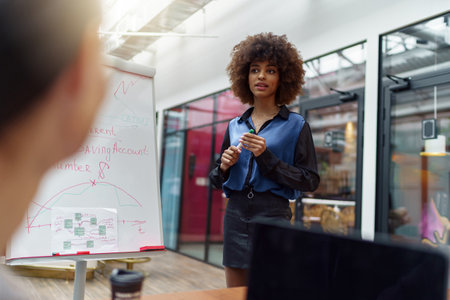 Female business coach or speaker make flip chart presentation to diverse businesspeople at meetingの写真素材