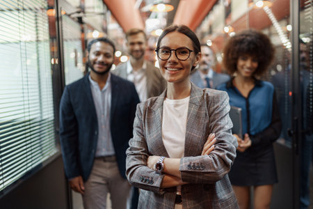 Portrait of smiling businesswoman in glasses standing in modern office on colleagues background