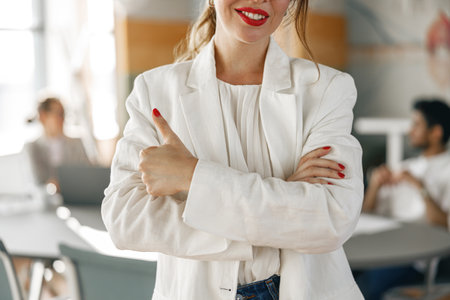 Close up businesswoman in white suit standing in office on colleagues background. Business concept
