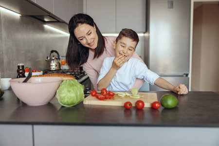 portrait of happy beautiful mother hugging small cute son while cooking together.の写真素材